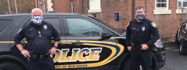 Two officers standing next to police car.